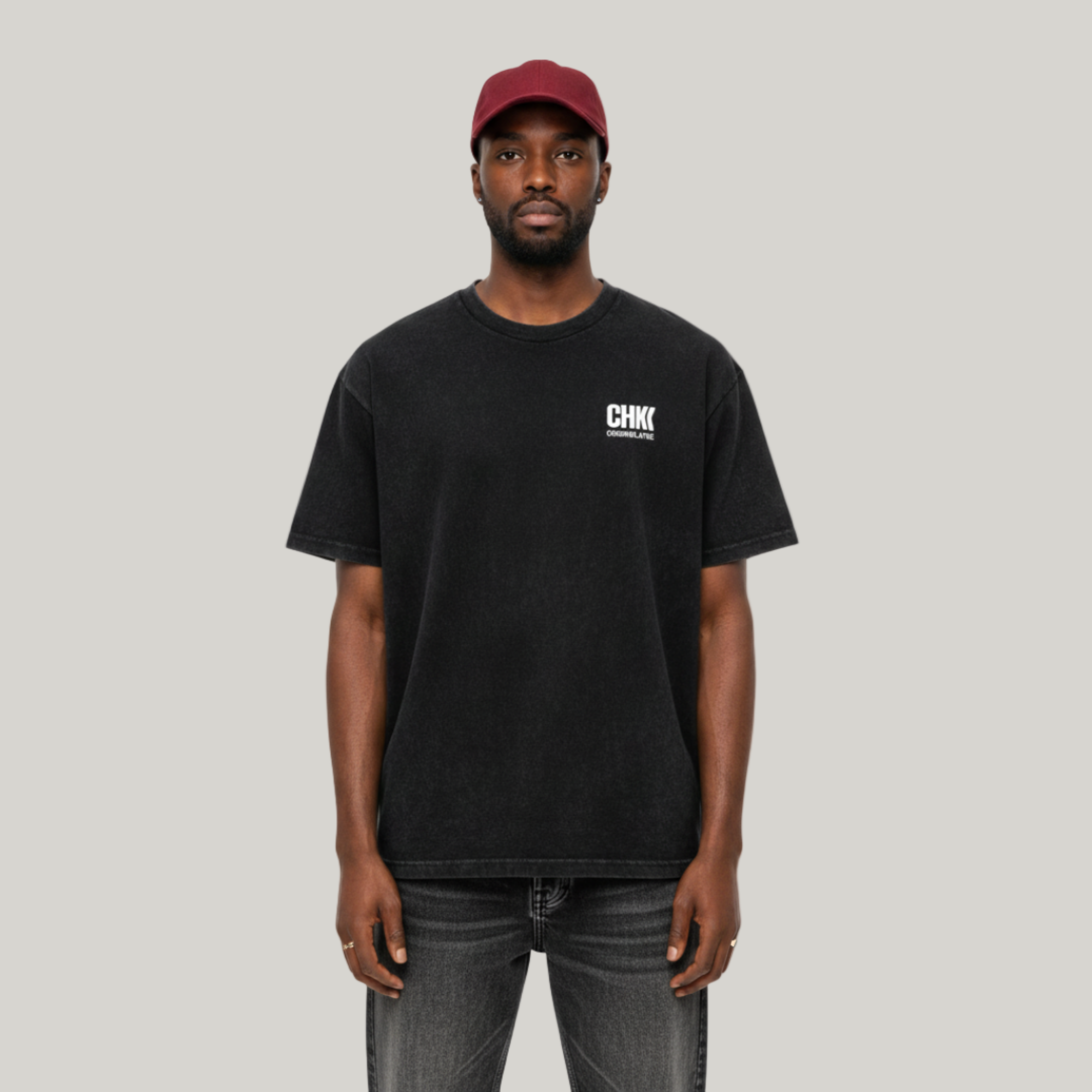 Person wearing a black t-shirt with a logo and a red cap on a white background